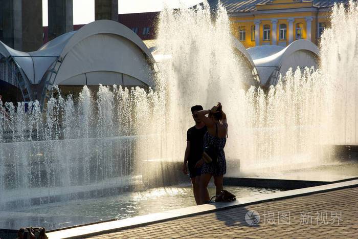 一对情侣在城市喷泉的背景下夏日酷暑