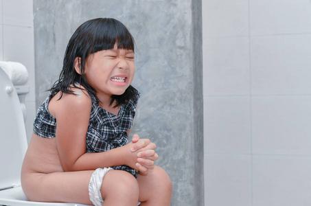 小鸭子的小女孩小女孩胃和坐在洗手间, 腹泻便秘并且健康概念照片